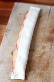 pastry strip folded up over the line of thinly sliced apples